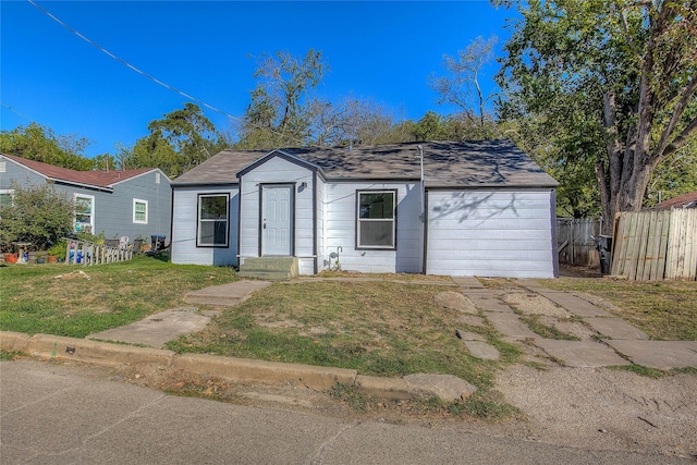 view of front of house featuring an attached garage, a front yard, and fence