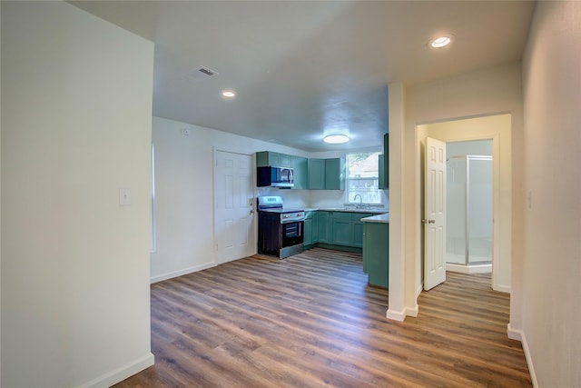 kitchen featuring dark wood finished floors, stainless steel appliances, visible vents, a sink, and baseboards