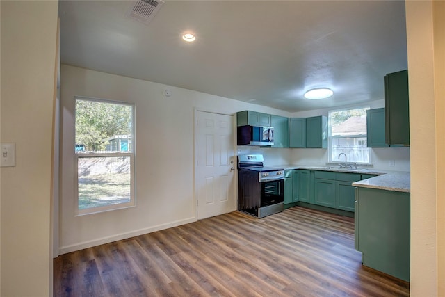 kitchen featuring visible vents, a sink, stainless steel appliances, light countertops, and green cabinetry