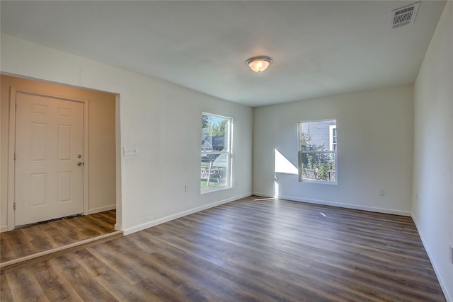 spare room with baseboards, plenty of natural light, visible vents, and dark wood-style flooring