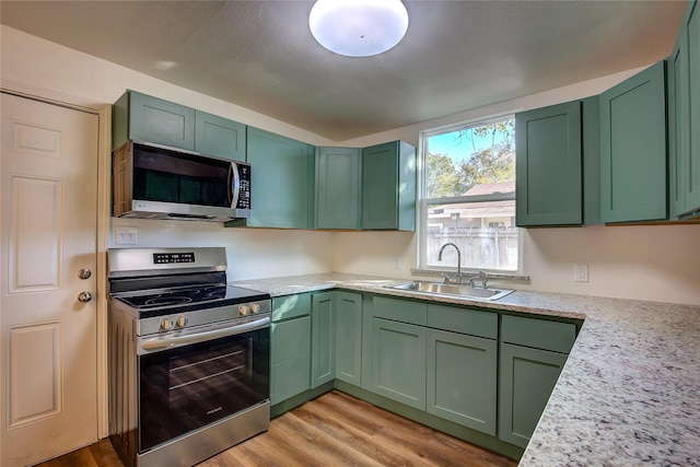 kitchen with appliances with stainless steel finishes, a sink, and green cabinetry