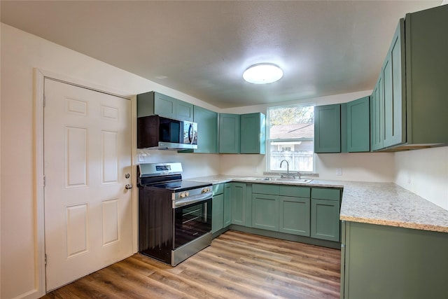 kitchen featuring stainless steel appliances, a sink, and green cabinetry