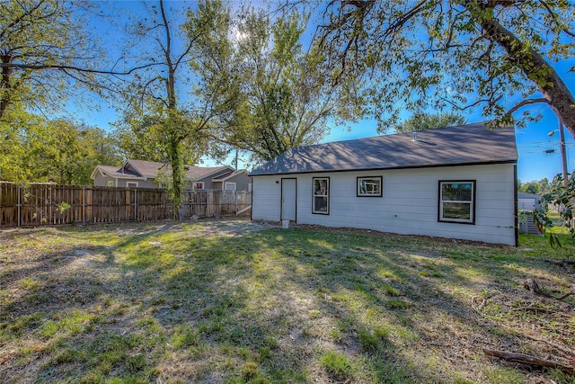 rear view of property with fence and a lawn