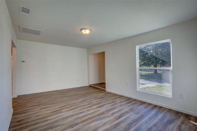 spare room featuring a healthy amount of sunlight, visible vents, and wood finished floors