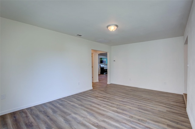 unfurnished room with baseboards, visible vents, and wood finished floors