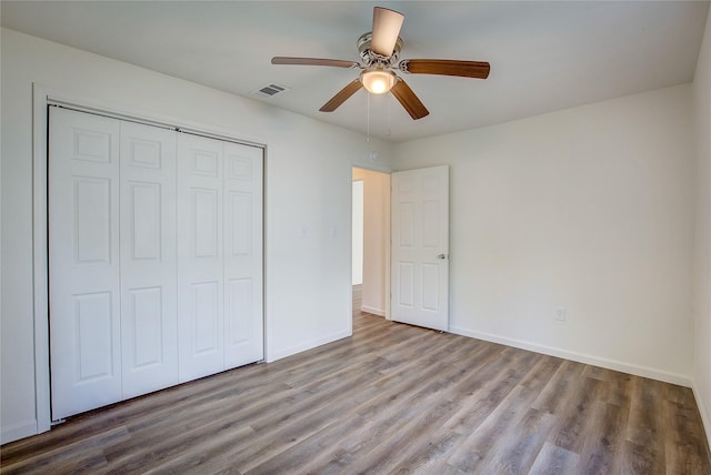 unfurnished bedroom featuring a closet, wood finished floors, visible vents, and baseboards