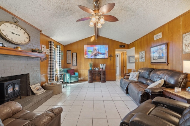 living room featuring lofted ceiling with beams, ceiling fan, light tile patterned floors, a textured ceiling, and wood walls