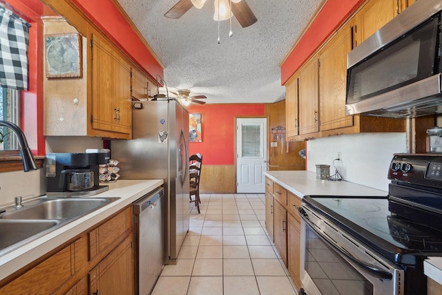 kitchen featuring appliances with stainless steel finishes, brown cabinets, light countertops, a textured ceiling, and a sink