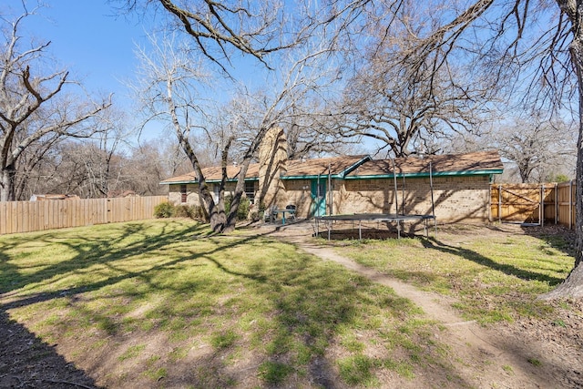 view of yard with a trampoline and a fenced backyard