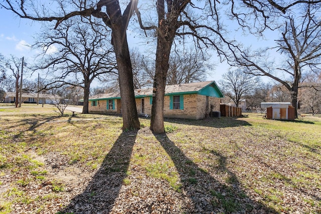 exterior space with a front yard, an outbuilding, and brick siding