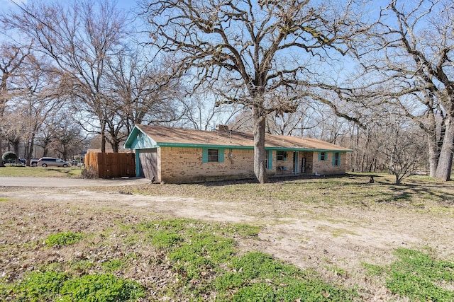 view of front of home with a garage, brick siding, fence, and driveway