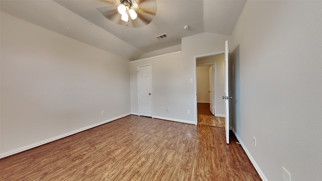 unfurnished bedroom with lofted ceiling, wood finished floors, visible vents, baseboards, and a closet