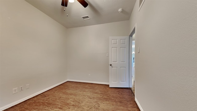 empty room with visible vents, ceiling fan, baseboards, and wood finished floors