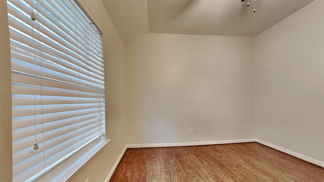 empty room featuring a wealth of natural light, baseboards, and wood finished floors