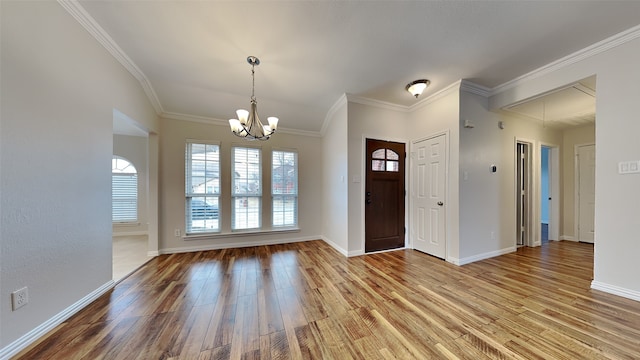 entryway featuring baseboards, ornamental molding, wood finished floors, and an inviting chandelier