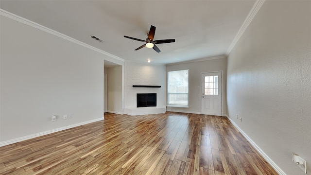 unfurnished living room with a large fireplace, baseboards, visible vents, ornamental molding, and wood finished floors