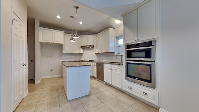 kitchen with backsplash, appliances with stainless steel finishes, a sink, dark stone counters, and under cabinet range hood