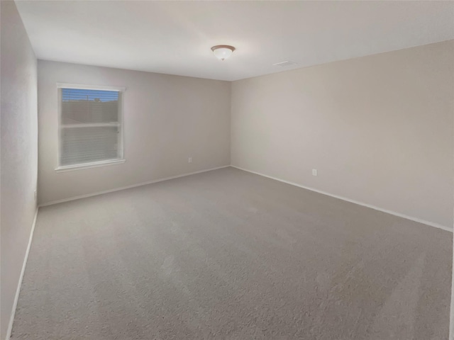 carpeted spare room featuring baseboards