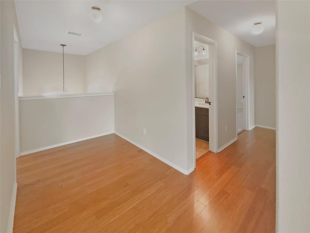 unfurnished room featuring light wood finished floors, baseboards, and visible vents