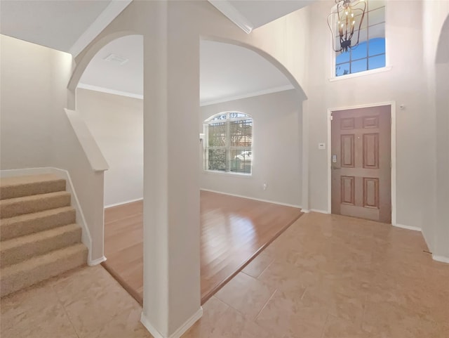 foyer entrance featuring visible vents, baseboards, a high ceiling, stairs, and a chandelier