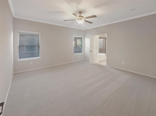 spare room with ceiling fan, carpet flooring, visible vents, baseboards, and crown molding