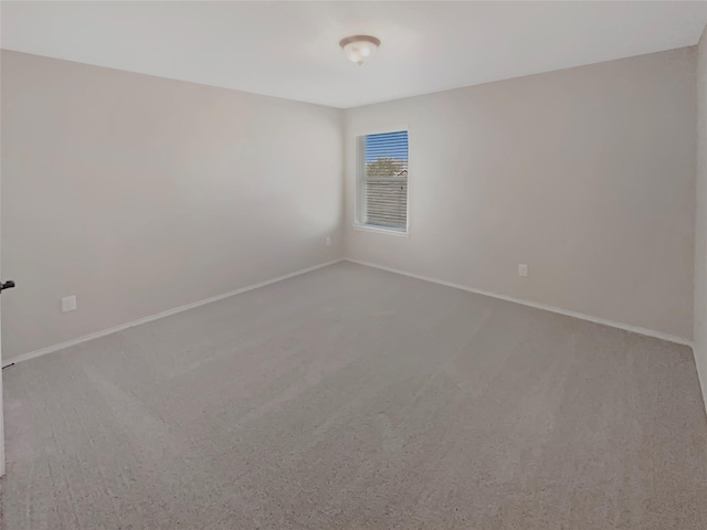 carpeted spare room featuring baseboards