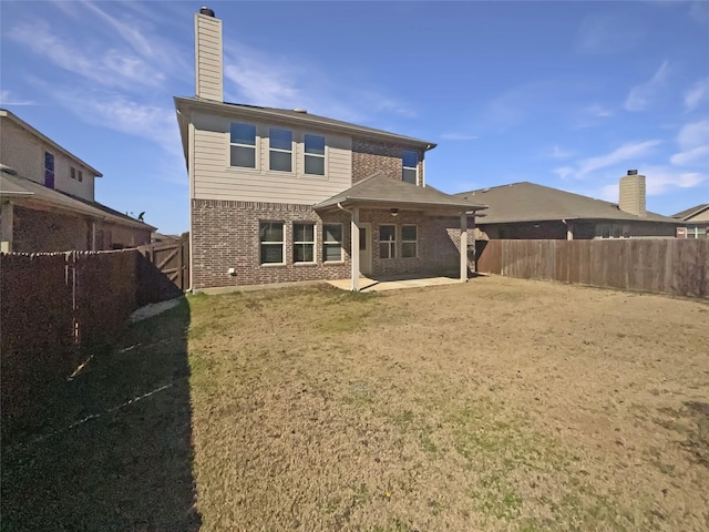 back of property with a patio, brick siding, a chimney, and a fenced backyard