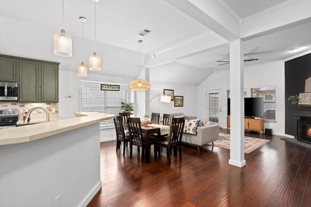 dining space with visible vents, crown molding, ceiling fan, dark wood finished floors, and a warm lit fireplace