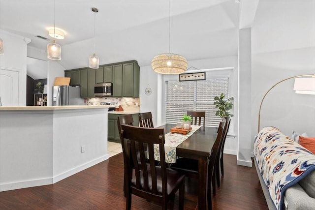 dining space with dark wood-type flooring, baseboards, visible vents, and vaulted ceiling