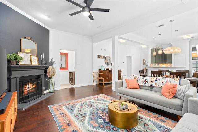 living room with visible vents, ornamental molding, a ceiling fan, wood finished floors, and a glass covered fireplace