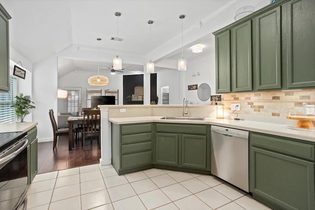 kitchen featuring green cabinetry, a peninsula, a sink, light countertops, and appliances with stainless steel finishes