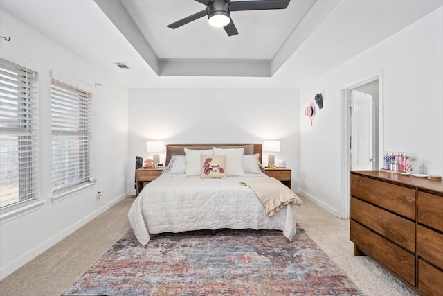 bedroom with visible vents, baseboards, carpet, a raised ceiling, and a ceiling fan