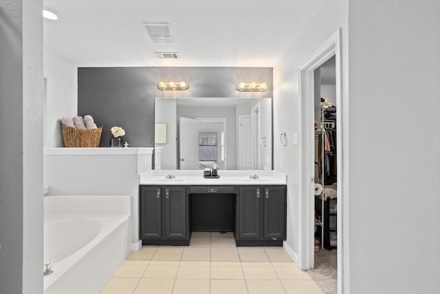 full bathroom featuring visible vents, a walk in closet, double vanity, a bath, and a sink