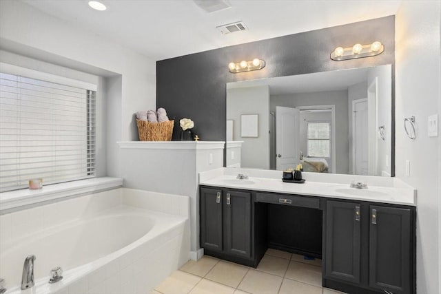 ensuite bathroom with tile patterned flooring, a garden tub, connected bathroom, and a sink