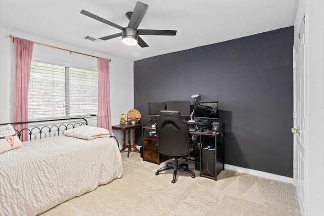 carpeted bedroom featuring an accent wall, baseboards, visible vents, and a ceiling fan