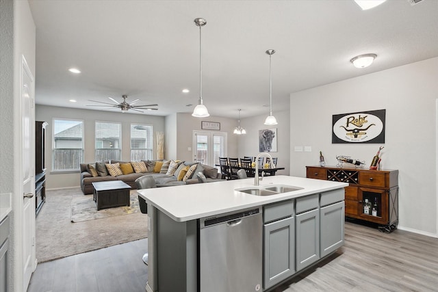 kitchen featuring open floor plan, light countertops, gray cabinets, stainless steel dishwasher, and a sink