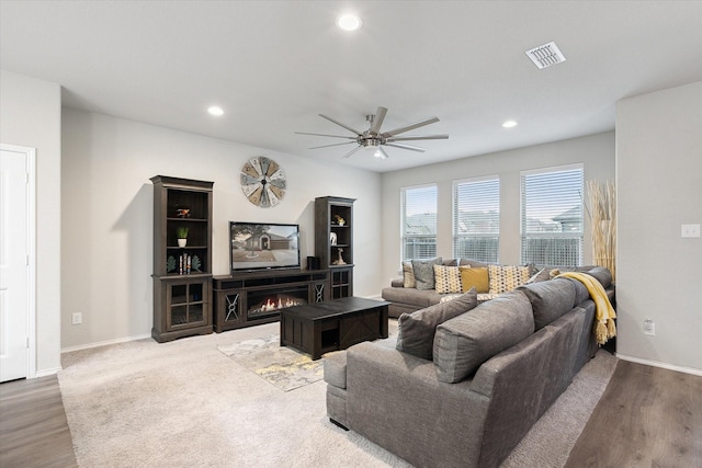 living area with a ceiling fan, recessed lighting, visible vents, and a lit fireplace