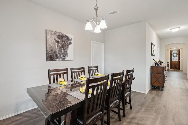 dining room with arched walkways, visible vents, an inviting chandelier, wood finished floors, and baseboards