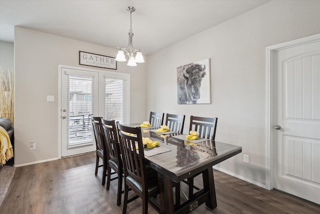 dining area with dark wood-style flooring, a notable chandelier, and baseboards