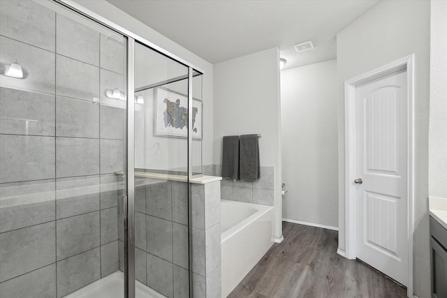 full bathroom featuring wood finished floors, visible vents, vanity, a bath, and a stall shower