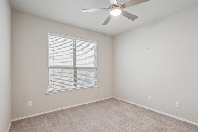 carpeted spare room with baseboards and a ceiling fan