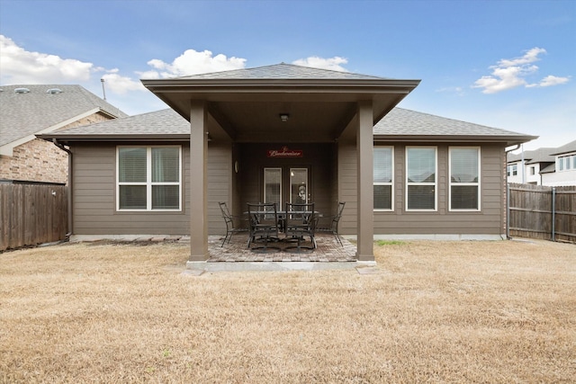 back of house with a yard, fence private yard, a patio area, and roof with shingles