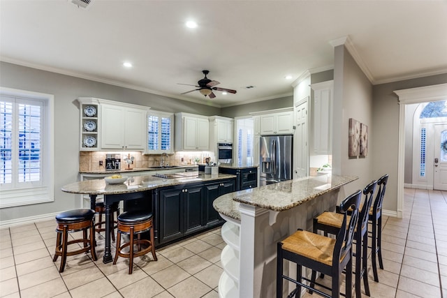 kitchen featuring light tile patterned floors, a kitchen island, appliances with stainless steel finishes, and a kitchen breakfast bar