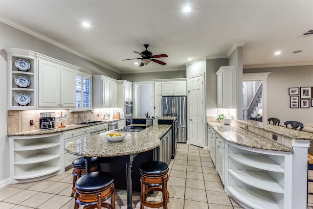 kitchen featuring a breakfast bar, appliances with stainless steel finishes, open shelves, and a sink