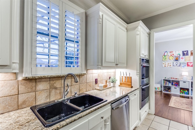 kitchen featuring tasteful backsplash, appliances with stainless steel finishes, ornamental molding, a sink, and light tile patterned flooring