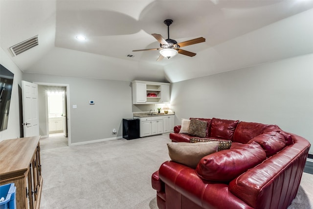 living area featuring lofted ceiling, light colored carpet, a ceiling fan, visible vents, and wet bar