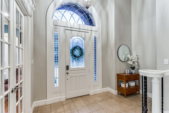 foyer entrance with a healthy amount of sunlight, baseboards, french doors, and light tile patterned flooring