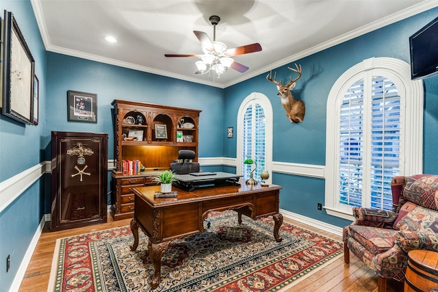 office featuring ceiling fan, a wainscoted wall, light wood-type flooring, and crown molding