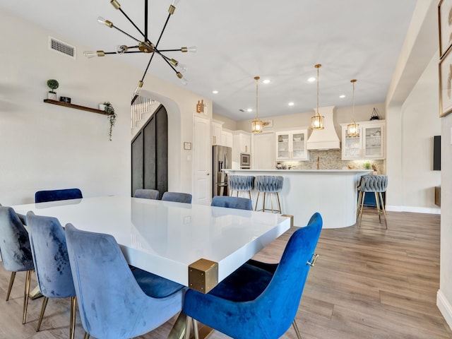 dining room with arched walkways, recessed lighting, visible vents, an inviting chandelier, and light wood-style floors