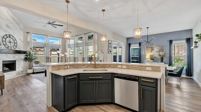 kitchen with a fireplace, light countertops, stainless steel dishwasher, open floor plan, and a sink